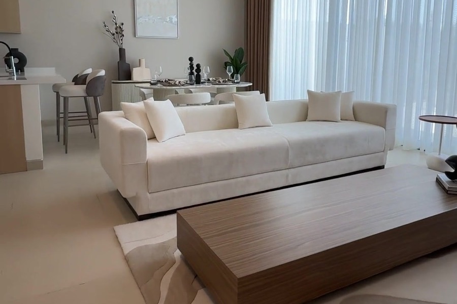 Helles Wohnzimmer mit weißem Sofa, Holztisch und bodentiefen Fenstern